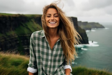 Environmental portrait photography of a joyful girl in her 20s wearing a relaxed flannel shirt at the cliffs of moher in county clare ireland. With generative AI technology - obrazy, fototapety, plakaty