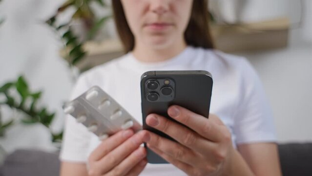 Selective focus of young woman using smartphone for searching online information about prescription pills label text about medical information online, instructions side effects, pharmacy medicament