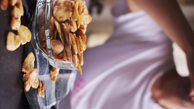 Vertical video of man taking some toast avas from glass pot on black background 
