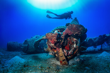 Fototapeta na wymiar A scuba diver explores a sunken world war two fighter propeller airplane at the seabed of the Aegean Sea, Naxos island, Greece