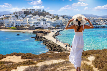 A tourist woman on summer vacations looks at the beautiful town of Naxos island, Cyclades, Greece