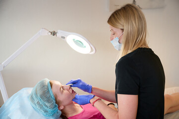 Cosmetologist injects substance in patient modifying face to make non-surgical correction. Filler...