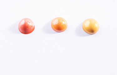 Three round swatches of different golden paint on white paper background. Bright pink gold, orange...