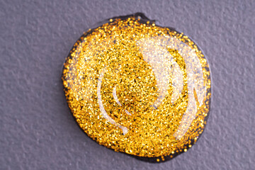 Round swatches of golden glitter paint on black paper background.