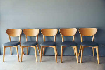 Row of wooden chair in job interview room with gray background.