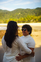 couple of women on the beach, dressed in white, lgbtqia+ representation, love between women