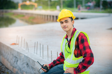 Engineer wearing a yellow hat Sit and look at the camera and smile.