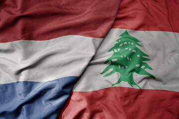 big waving national colorful flag of netherlands and national flag of lebanon .