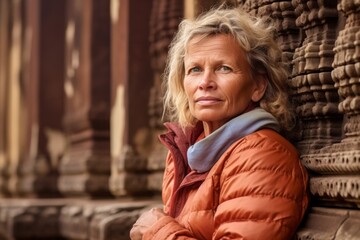 Naklejka premium Medium shot portrait photography of a glad mature woman wearing a quilted insulated jacket at the angkor wat in siem reap cambodia. With generative AI technology