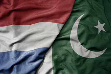 big waving national colorful flag of netherlands and national flag of pakistan .