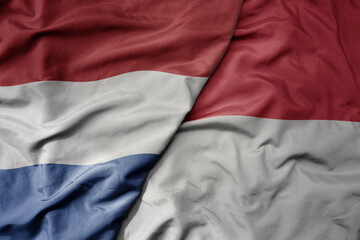 big waving national colorful flag of netherlands and national flag of indonesia .