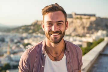 Headshot portrait photography of a grinning boy in his 30s wearing a trendy cropped top in front of the acropolis in athens greece. With generative AI technology - obrazy, fototapety, plakaty