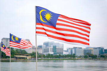 The Malaysia flag is also known as Jalur Gemilang waving with a city in the background. Independence Day or Merdeka Day celebration on 31 August and Hari Malaysia on 16 September, copy space concept.
