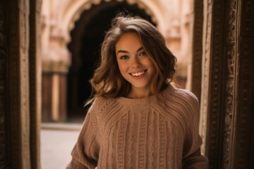 Lifestyle portrait photography of a joyful girl in her 20s wearing a warm wool sweater at the alhambra in granada spain. With generative AI technology - obrazy, fototapety, plakaty