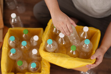 A man hand holding paper garbage bin collecting plastic bottle at his home.