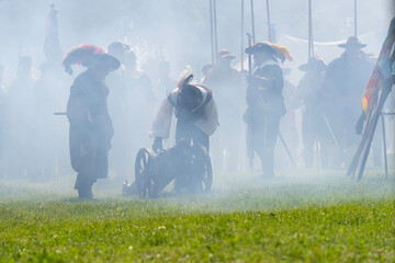 Medieval mercenaries shrouded in gunpowder smoke fire cannons
