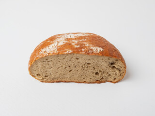 A slice of fresh round loaf of bread on a white table.