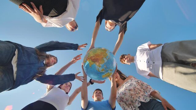 Friends holding a geographical globe in their hands. The concept of keeping the world safe.
