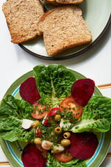 Fresh colorful spring vegetable salad with cherry tomatoes and beetroot in green plate. Healthy organic vegan lunch or snack close up.