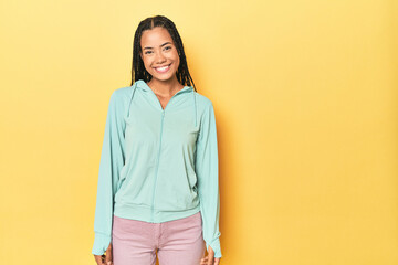 Indonesian sporty woman on yellow backdrop happy, smiling and cheerful.