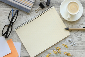Office desk with empty notebook and coffee cup. glasses and yellow fiddlers