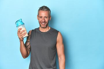 Athlete with protein shake on blue studio backdrop