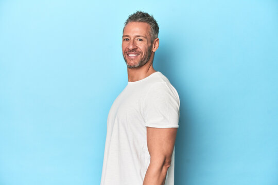 Middle-aged man posing on blue studio backdrop