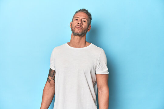 Middle-aged man posing on blue studio backdrop
