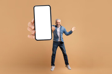 Handsome stylish mature man jumping with huge phone in hand