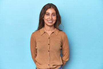 Fototapeta premium Teen girl in brown polo shirt on blue happy, smiling and cheerful.