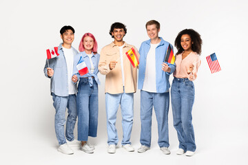 Happy exchange students in language school. Smiling multiracial friends holding different flags over white background