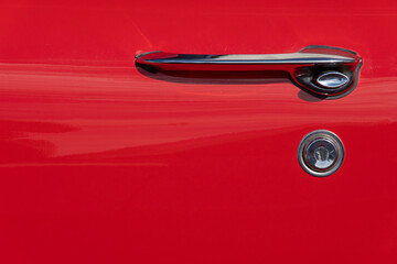 detail of the door Old red car with chrome details and two-tone black and white tire.