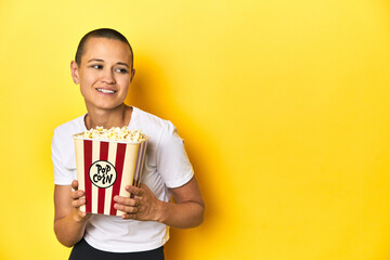 Young woman eating popcorn, cinema concept, yellow backdrop