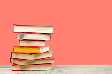 Composition with hardback books on wooden deck table and orange background. Books stacking. Back to...