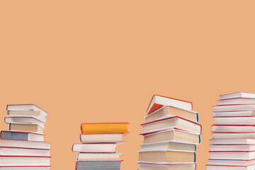 Composition with hardback books on wooden deck table and orange background. Books stacking. Back to school. Copy Space. Education background.