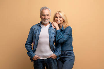 Happily married mature couple posing on beige background