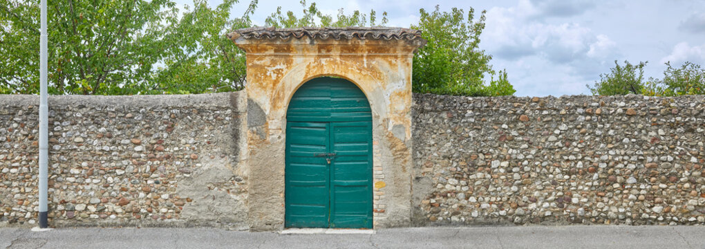 Typical rustic park wall with beautiful gate in Tuscany. In panoramic format.