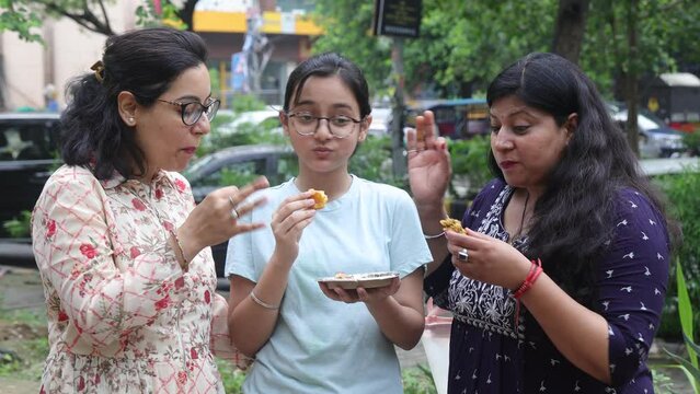 Girls eating pakora. Indian Girls having Indian street food like pakoras. Cool Mid aged Girls having Indian street food like pakoras