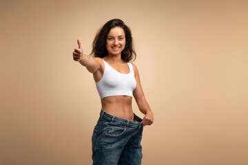 Slim indian young lady pulling her jeans showing thumb up