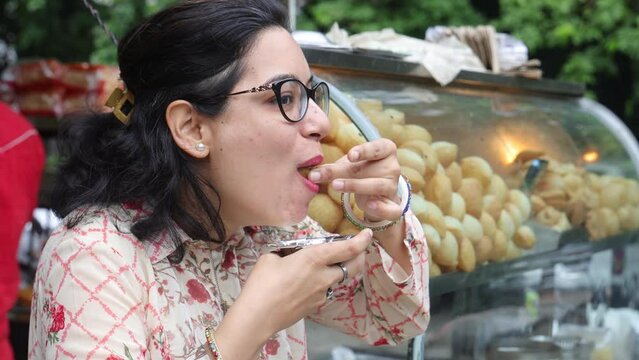 Happy Indian woman having North Indian subcontinent popular street food. Hand cracking panipuri. Street food. Appetizer.