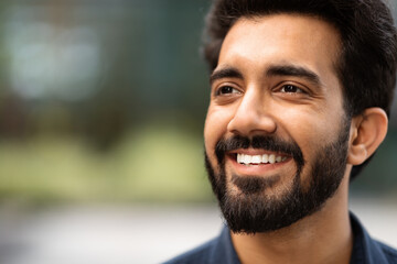 Closeup of cheerful handsome indian guy looking at copy space