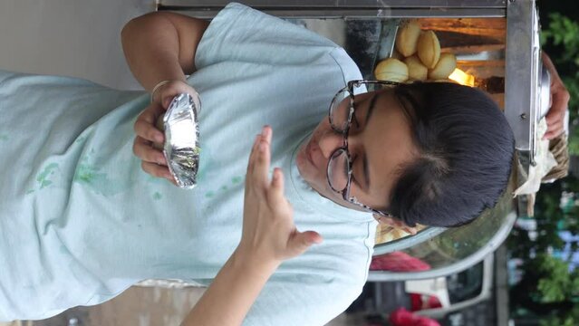Happy Indian woman having North Indian subcontinent popular street food. Hand cracking panipuri. Street food. Appetizer.