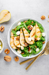 Grilled Pear Salad, Salad with Pear, Arugula, Mozzarella Pearls, Walnuts and Dressing over Bright Background
