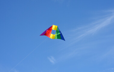 A colorful stunt kite with rainbow colors in the blue sky