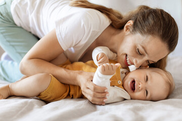 Happy young mother and toddler child bonding in bed
