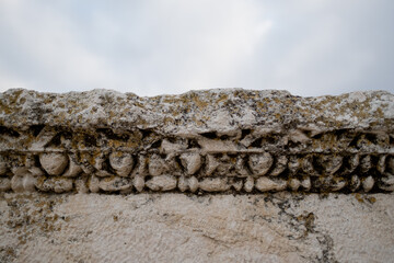 Closeup of beaded carvings along the edge of a block, part of a grand, monumental Roman ruin at...