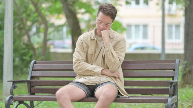 Tired Casual Young Man Sleeping while Sitting on Bench
