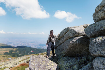 Obraz premium Woman sitting high in the summer mountain with stunning view 
