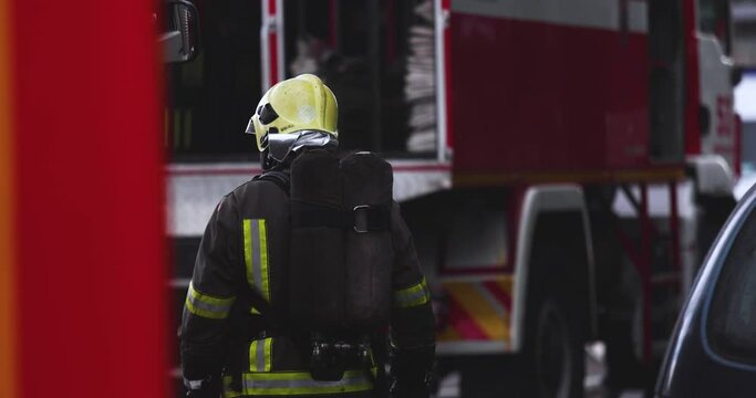 Group of fire men in uniform during blaze, fire fighting operation in the city streets, firefighters with the fire engine truck fighting vehicle in the background, emergency and rescue, slow motion