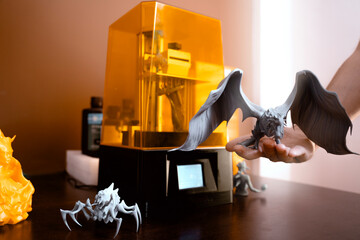 3d Printer , printing while man holding creatures made with it 